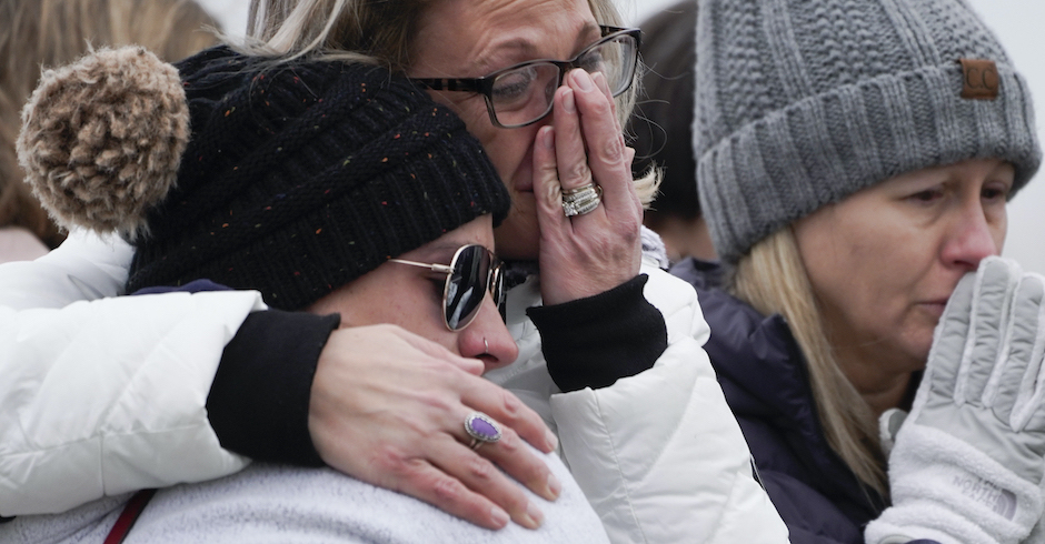Drei Frauen in Winterkleidung umarmen einander weinend