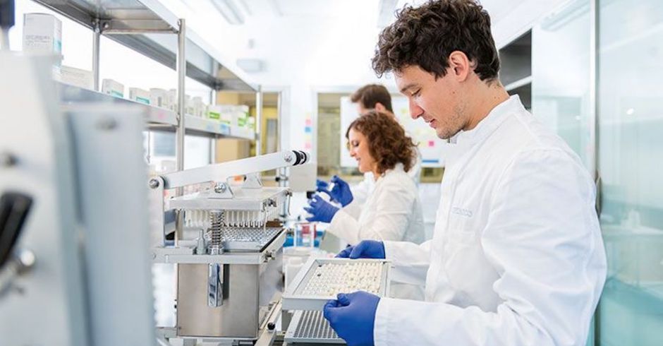 Blick in ein Labor mit mehreren Mitarbeitern in weißen Kitteln