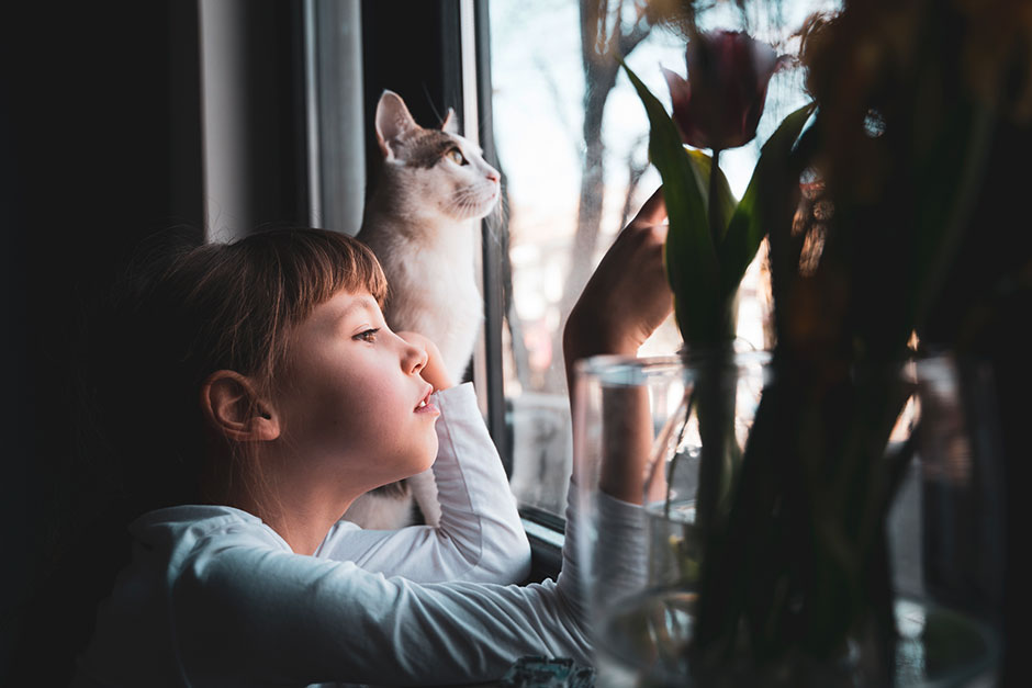 Mädchen blickt mit ihrer Katze aus dem Fenster | Credit: iStock.com/flyparade