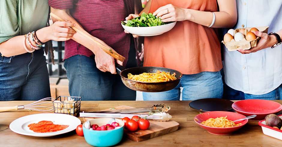 Junge Menschen beim gemeinsamen Essen im Stehen | Credit: iStock.com/Rawpixel