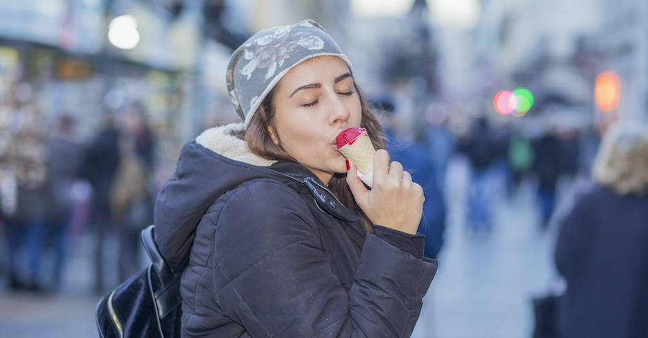 Frau isst im Winter ein Eis auf der Straße