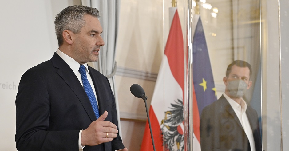 Bundeskanzler Karl Nehammer neben Gesundheitsminister Wolfgang Mückstein bei einer Pressekonferenz. Im Hintergrund die österreichische und europäische Flagge
