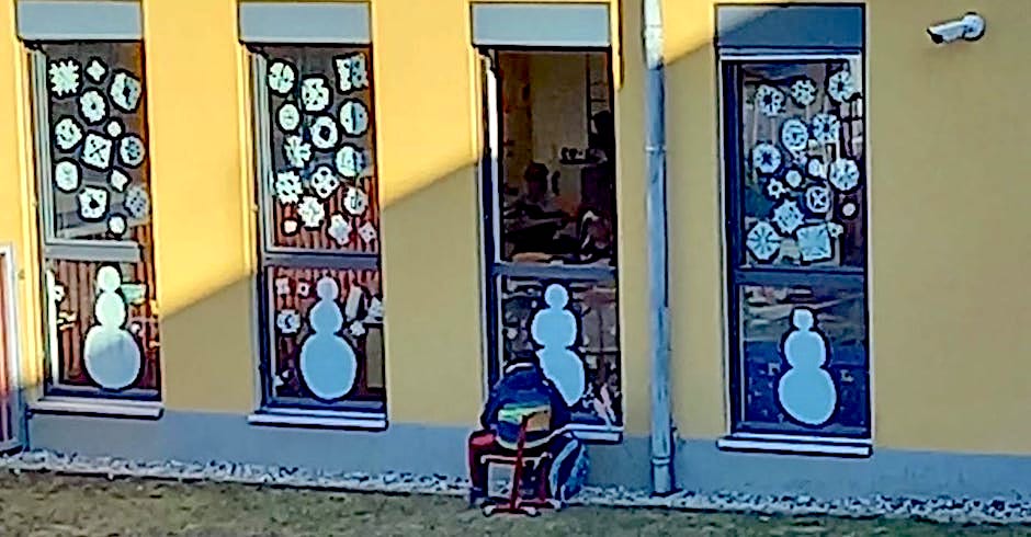 Schüler auf einem Sessel draußen vor dem Schulfenster