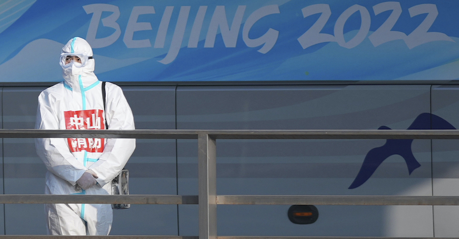 Mann in Schutzkleidung vor Beijing 2022 Schriftzug