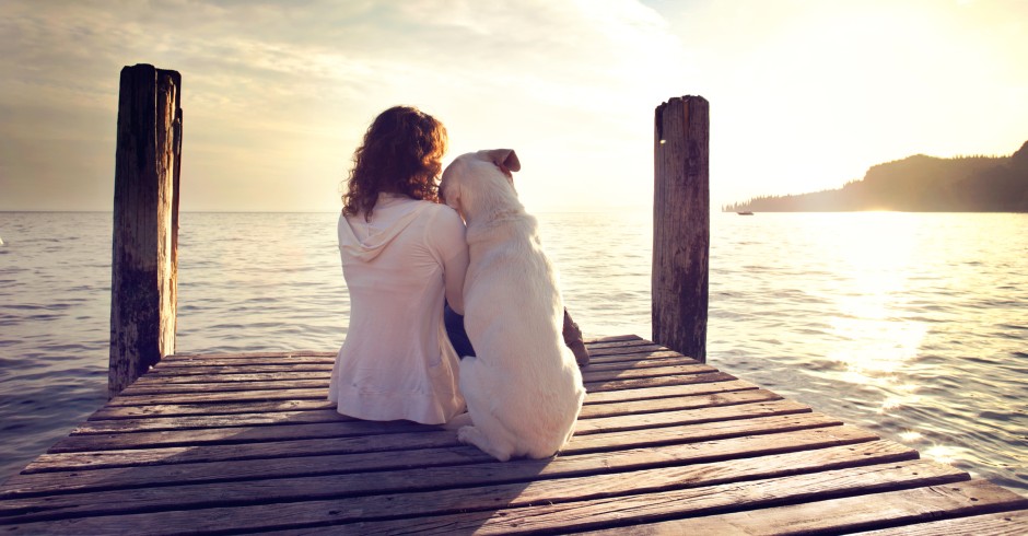 Frau und Hund sitzen am See | Credit: iStock.com/fcscafeine