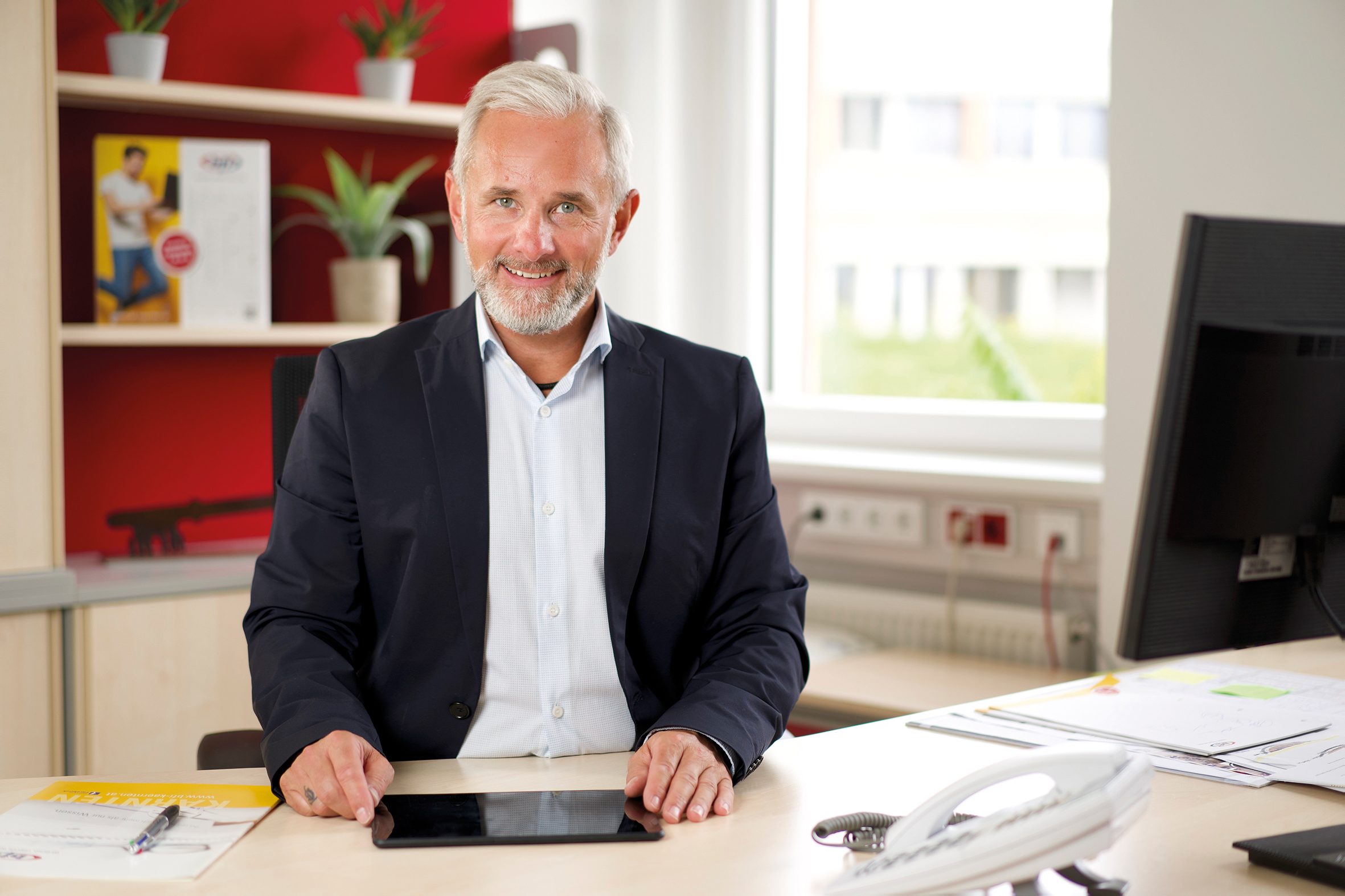 Der Geschäftsführer des bfi, Gottfried Pototschnig, sitzt an seinem Schreibtisch vor einem Tablet-PC