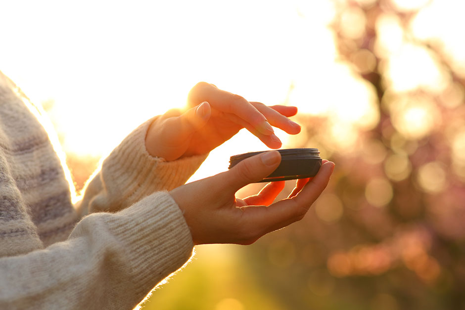 Frau hält geöffneten Cremetiegel in der Hand | Credit: iStock.com/Pheelings Media