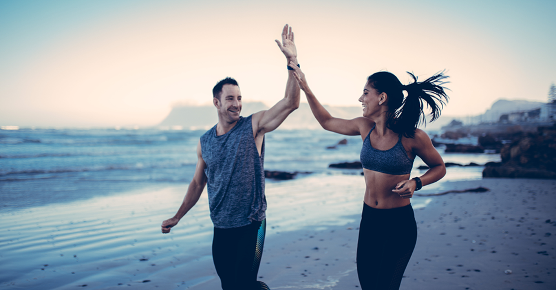 Sportliches Paar klatscht sich während dem Lauftraining am Strand ab | Credit: iStock.com/criene