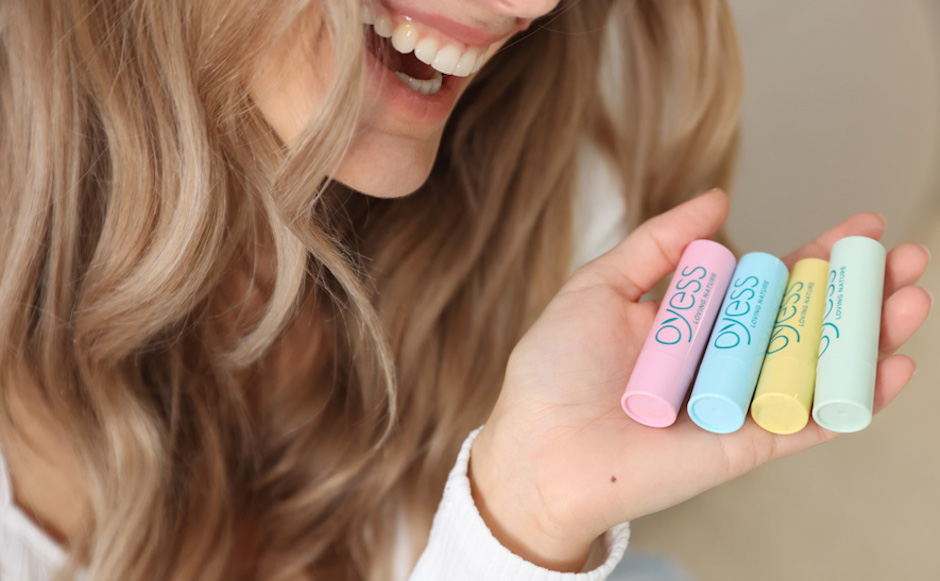 Junge Frau hält vier Lippenpflegestifte in der offenen Hand