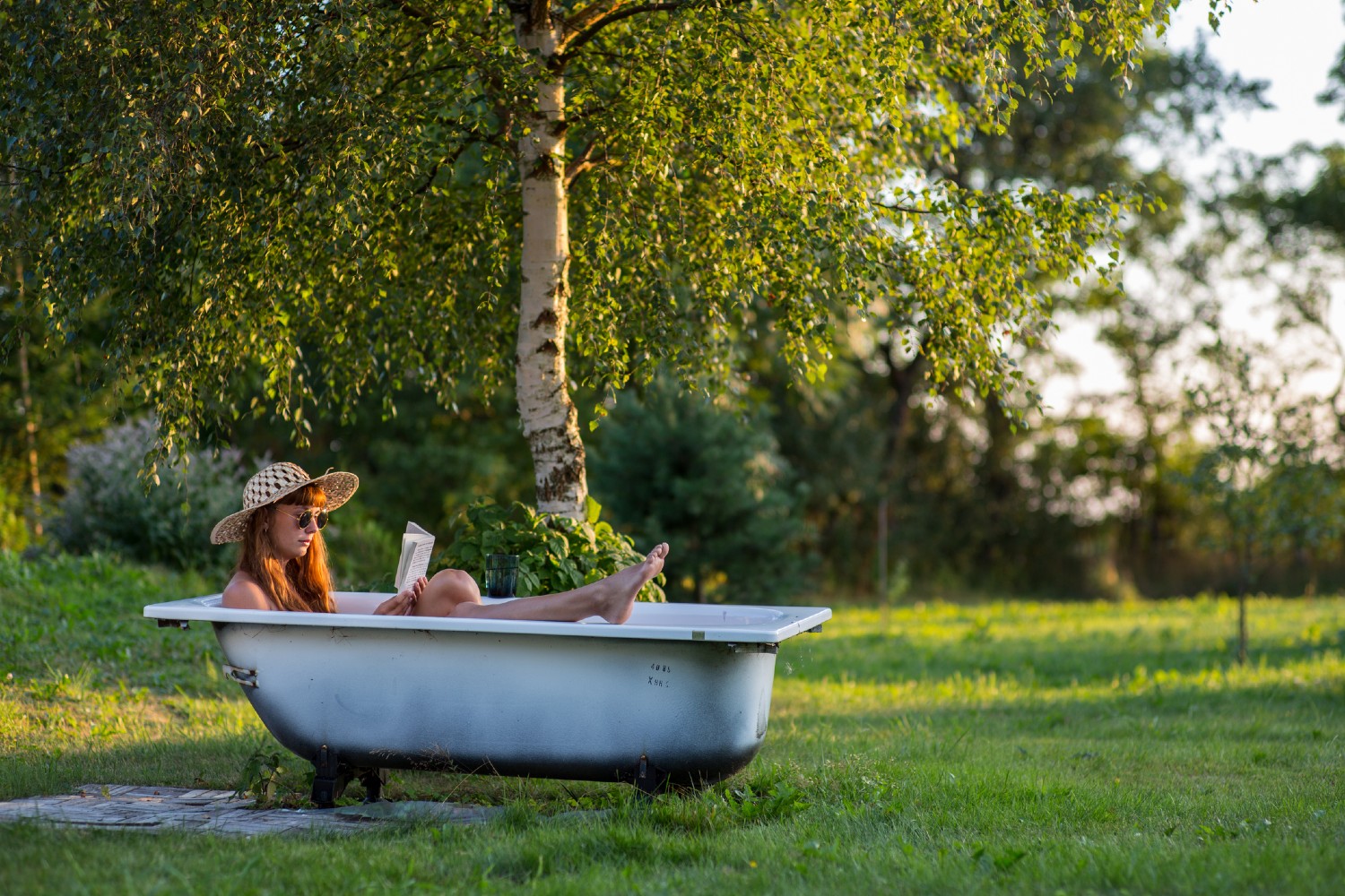 Frau sitzt im Garten in einer Badewanne | Credit: iStock.com/Jedraszak