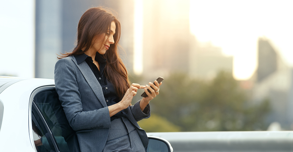 Frau checkt ihr Smartphone vor der Fahrt | Credit: iStock.com/gorodenkoff