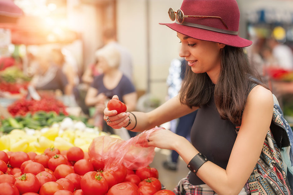 Frau testet beim Markteinkauf die Frische von Tomaten | Credit: iStock.com/guruXOOX
