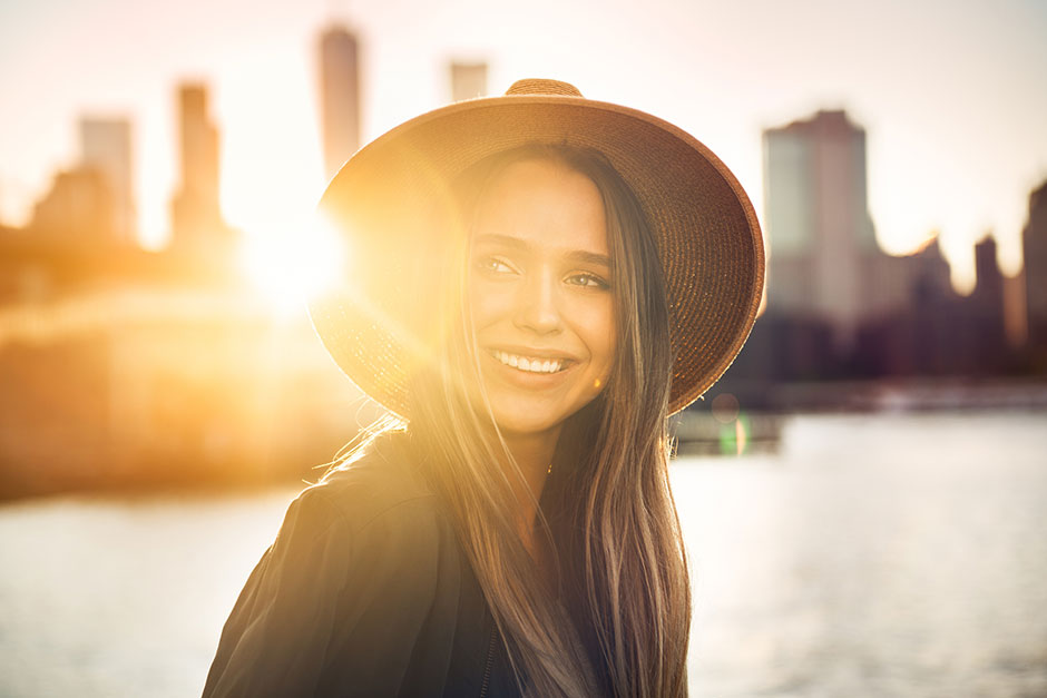 Glückliche Frau bei Sonnenaufgang vor städtischer Kulisse | Credit: iStock.com/JANIFEST