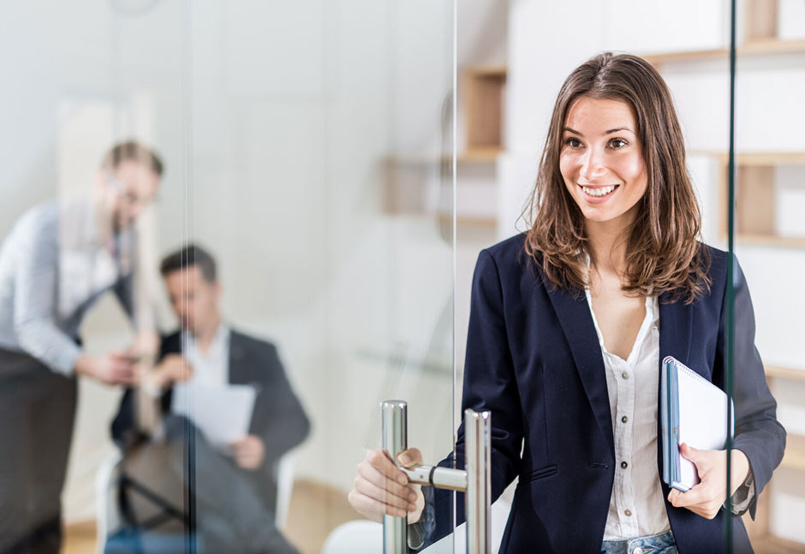 Frau verlässt das Büro, in dem zwei Kollegen miteinander sprechen | Credit: iStock.com/zoff-photo