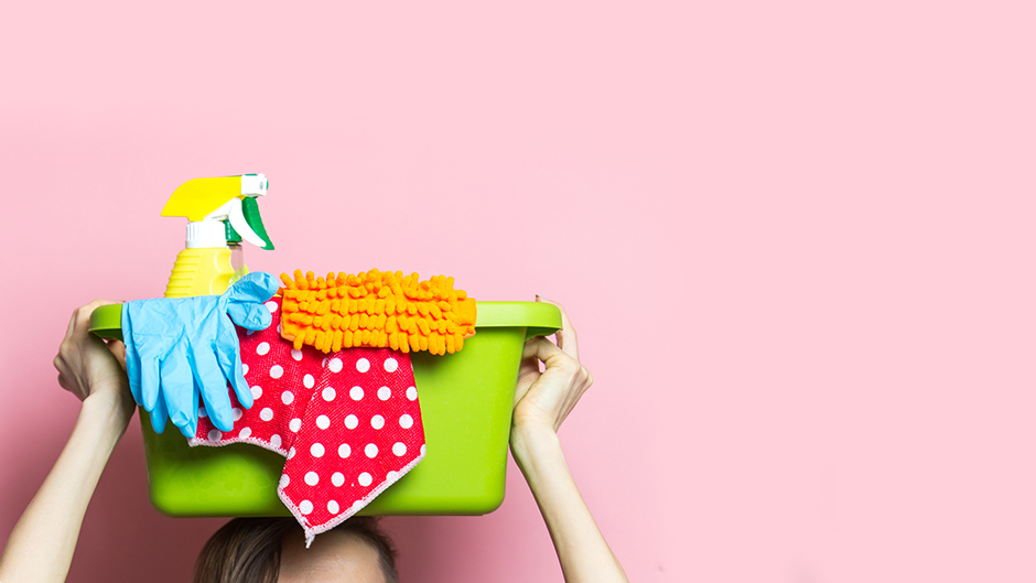 Junge Frau mit einer kleinen Wanne mit Putzmittel auf dem Kopf | Credit: iStock.com/Happycity21