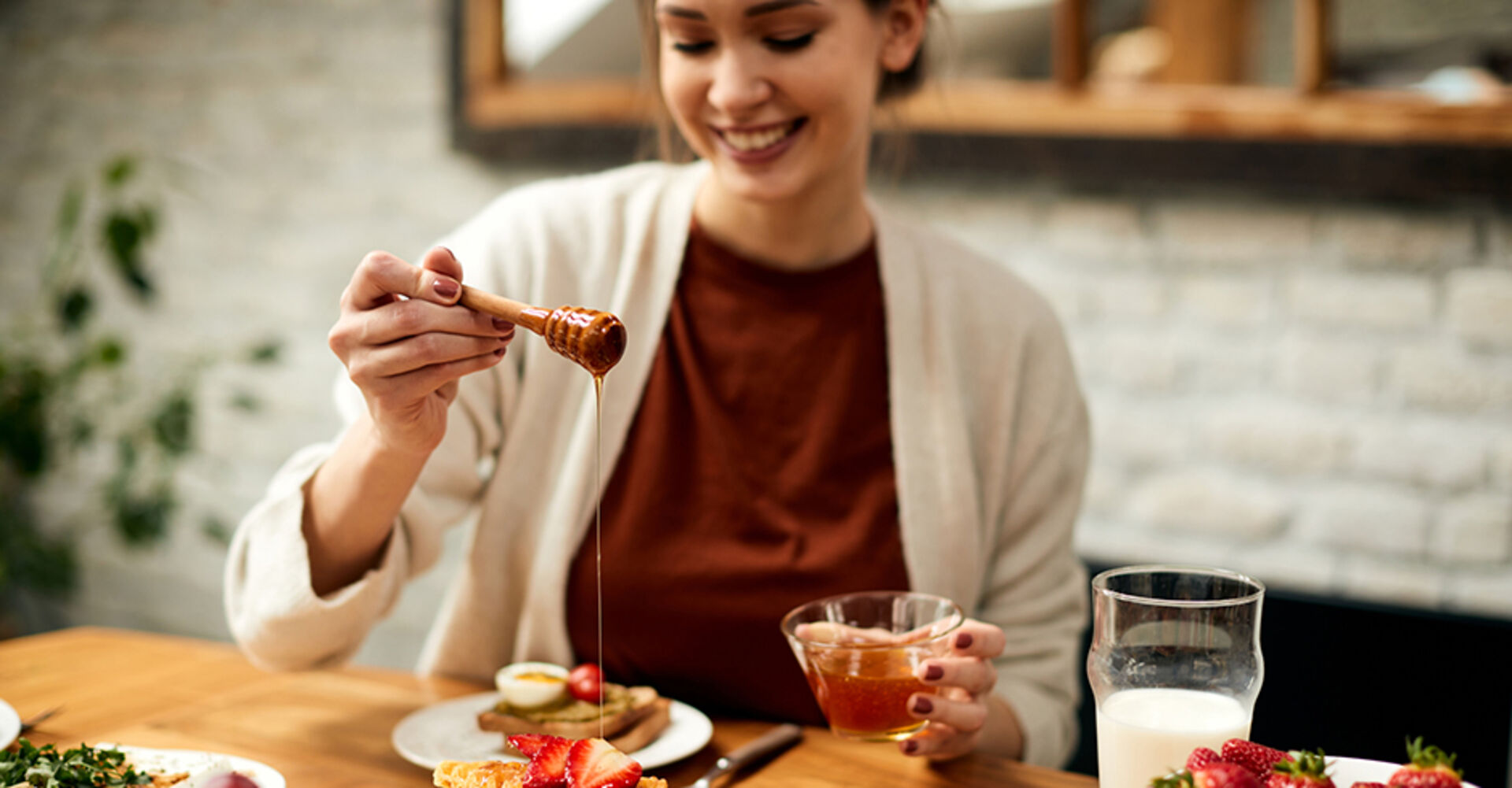 Junge Frau süßt mit Honig ihr Frühstück | Credit: iStock.com/Drazen Zigic