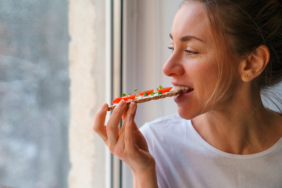 Genüsslich isst eine junge Frau ein Brot mit Kresse | Credit: iStock.com/Dima Berlin