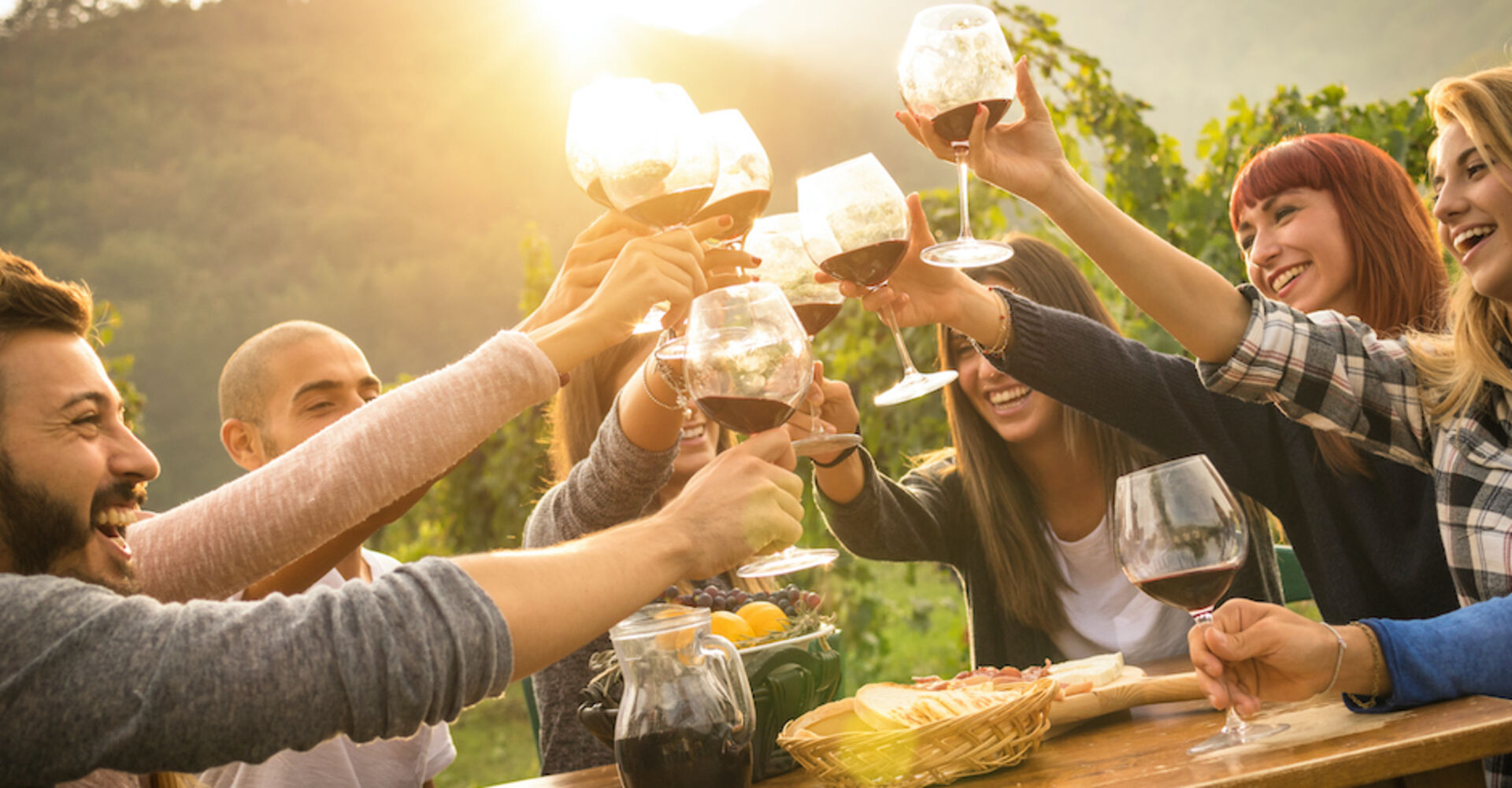 Freunde sitzen an einem Tisch im Weingarten | Credit: iStock.com/ViewApart