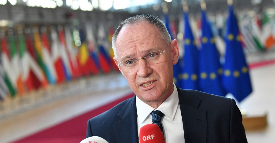 Gerhard Karner gibt ein Pressestatement im europäischen Parlament. Im Hintergrund die Flaggen der Mitgliedsländer und der Union.