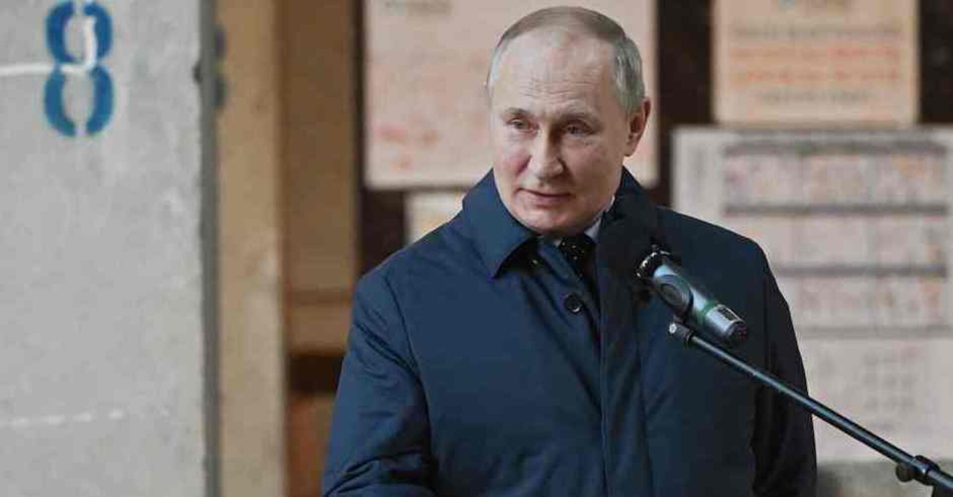 Putin in blauem Mantel, davor ein Mikrofonständer