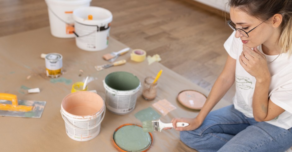 Frau sitzt mit Malutensilien am Boden | Credit: iStock.com/SolisImages