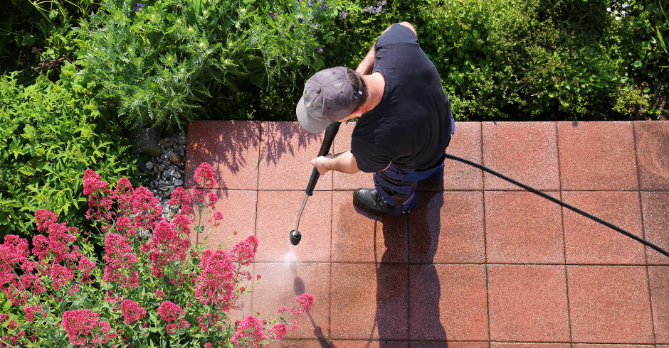 Mann reinigt Terrasse | Credit: iStock.com/Marina Lohrbach