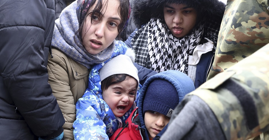 Eine Frau steht in einer Menschenmenge. Sie hält ein schreiendes Kind.