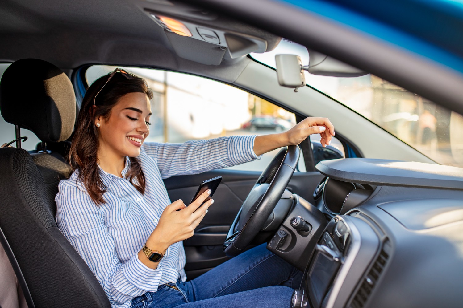 Frau sitzt mit Handy im Auto | Credit: iStock.com/dragana991