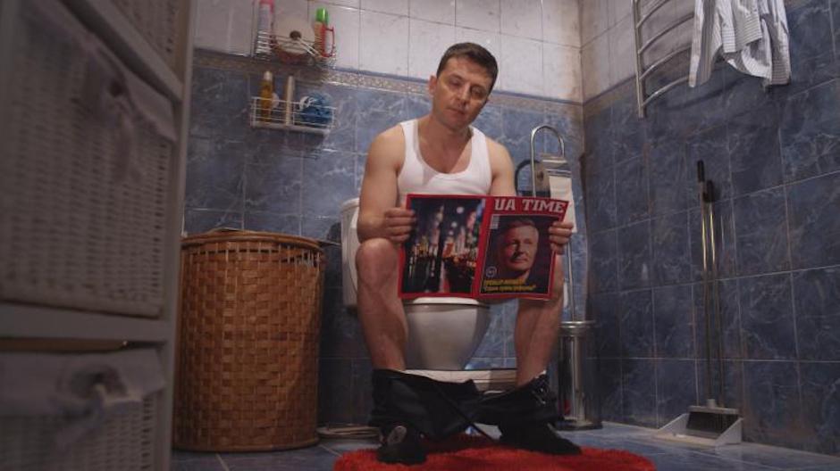 Szenenbild, auf der Toilette sitzend