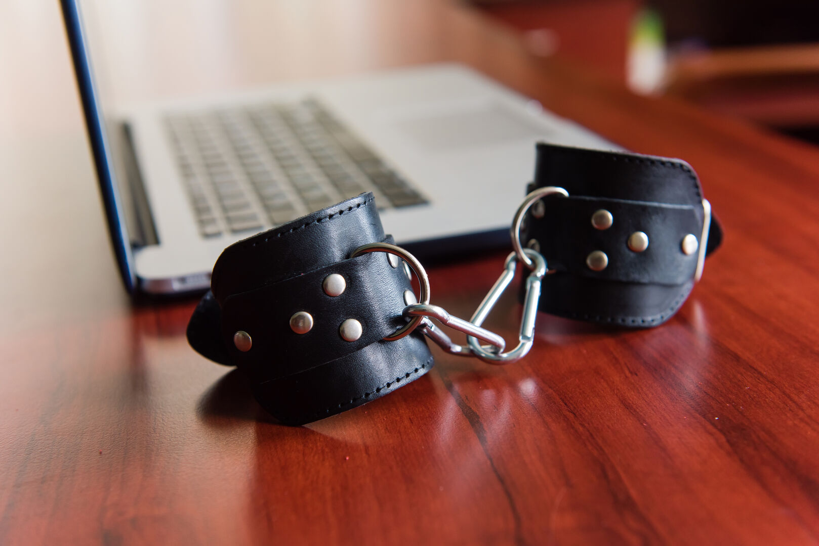 Handfesseln liegen neben Laptop | Credit: iStock.com/O_Lypa