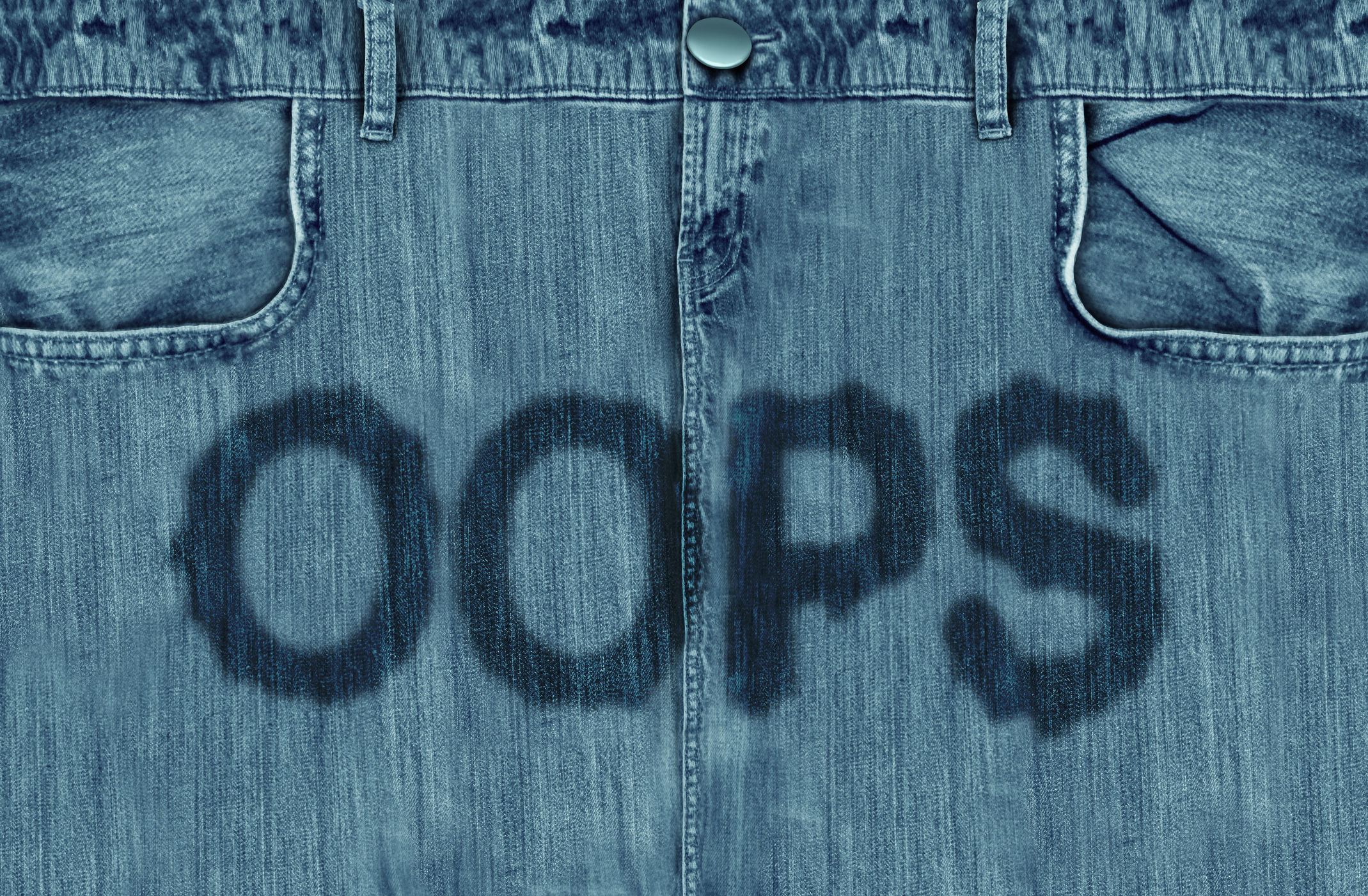 Nahaufnahme einer Jeans mit feuchtem Oops-Schriftzug im Schritt