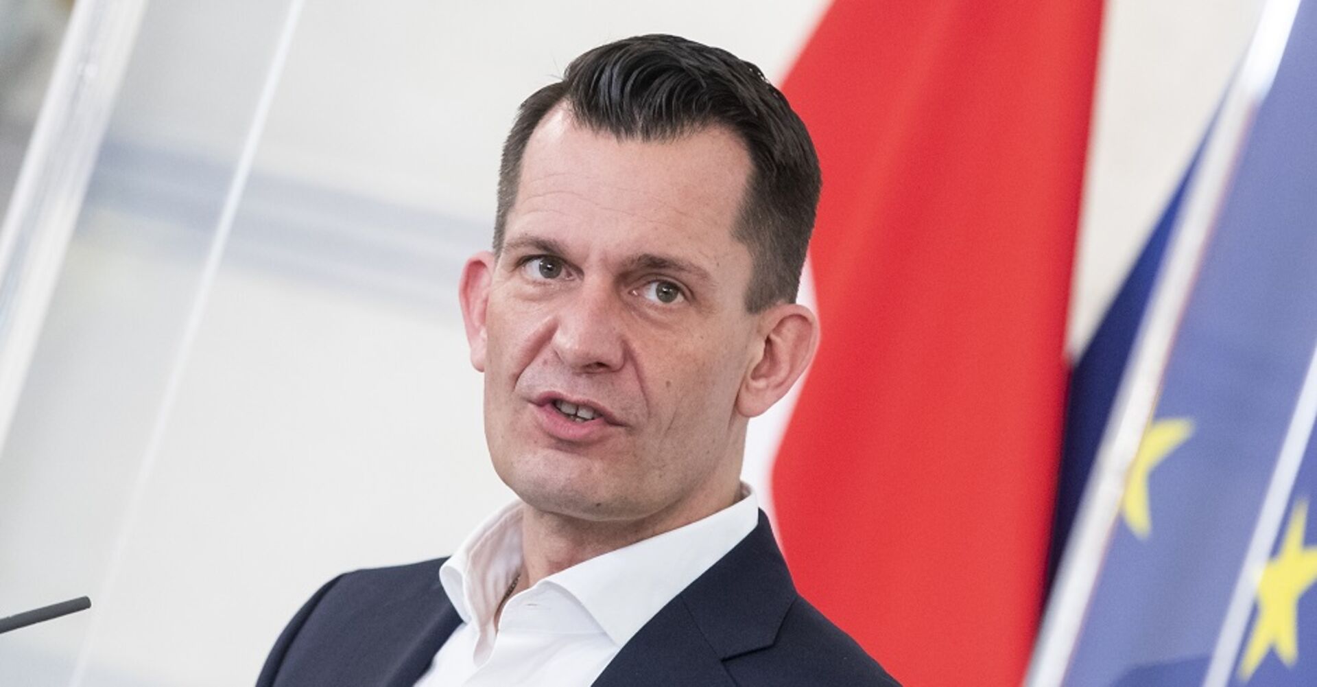 Gesundheitsminister Wolfgang Mückstein vor der Flaggen Österreichs und der EU