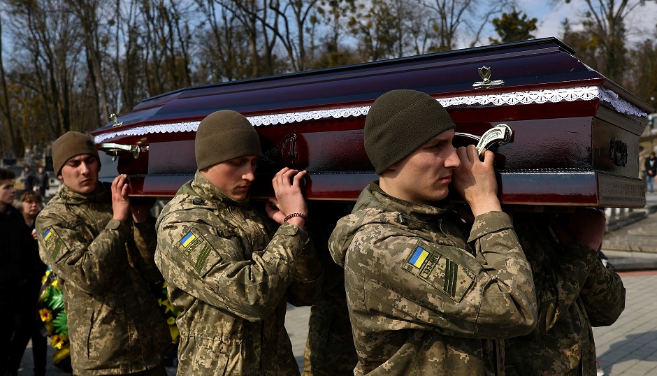 Junge Soldaten tragen einen Sarg.