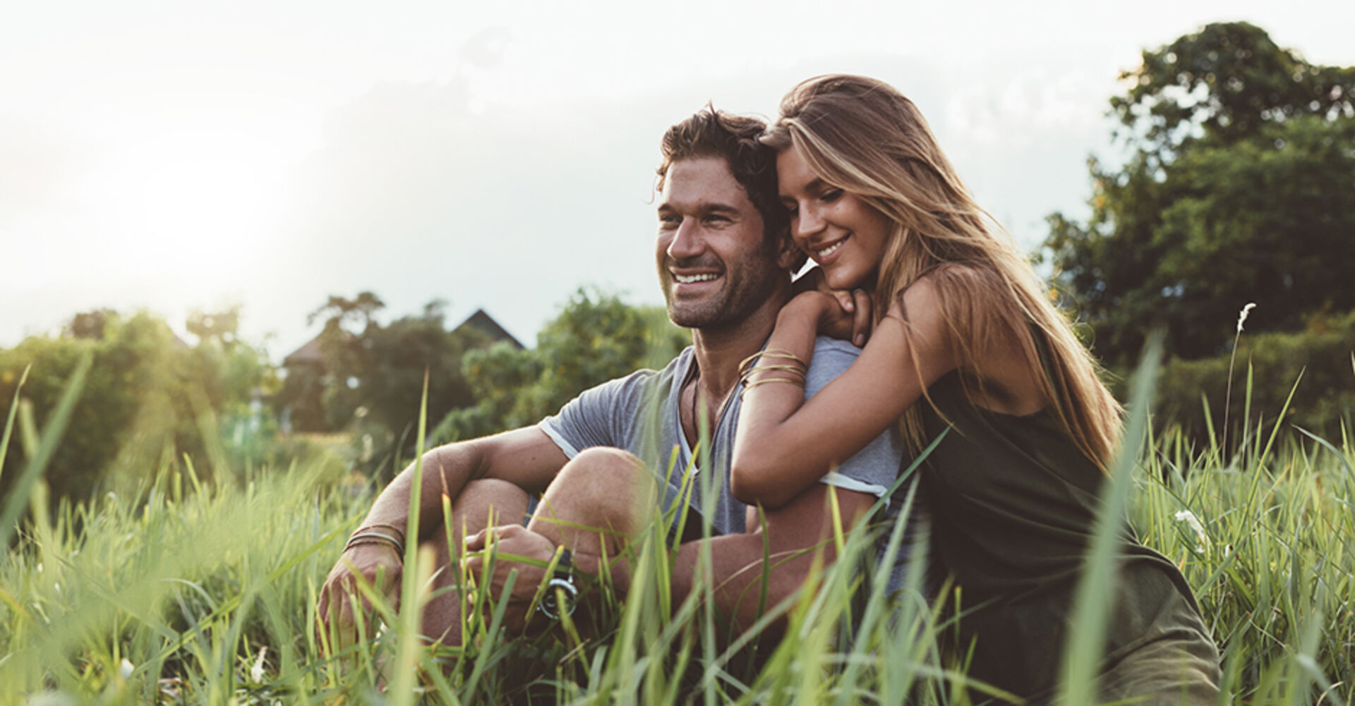 Junges verliebtes Paar sitzt an einem heißen Sommertag gemeinsam in der Wiese | Credit: iStock.com/Jacob Ammentorp Lund