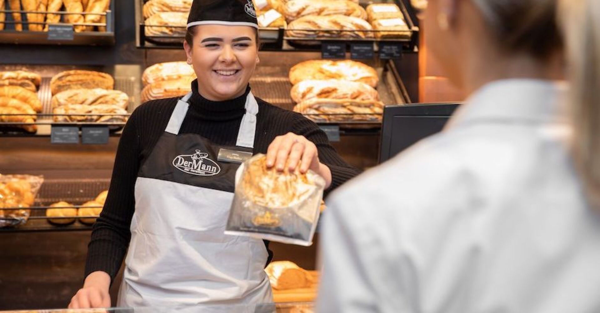Verkäufern reicht Kundin ihren Einkauf