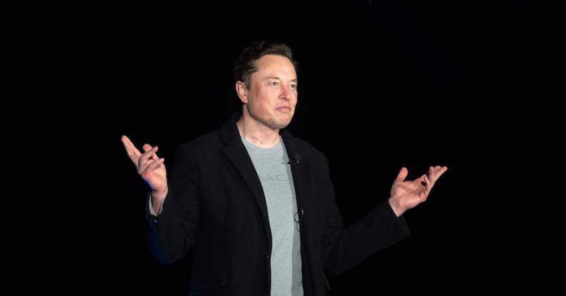 Porträt mit beidseitig erhobenen Händen vor schwarzem Hintergrund