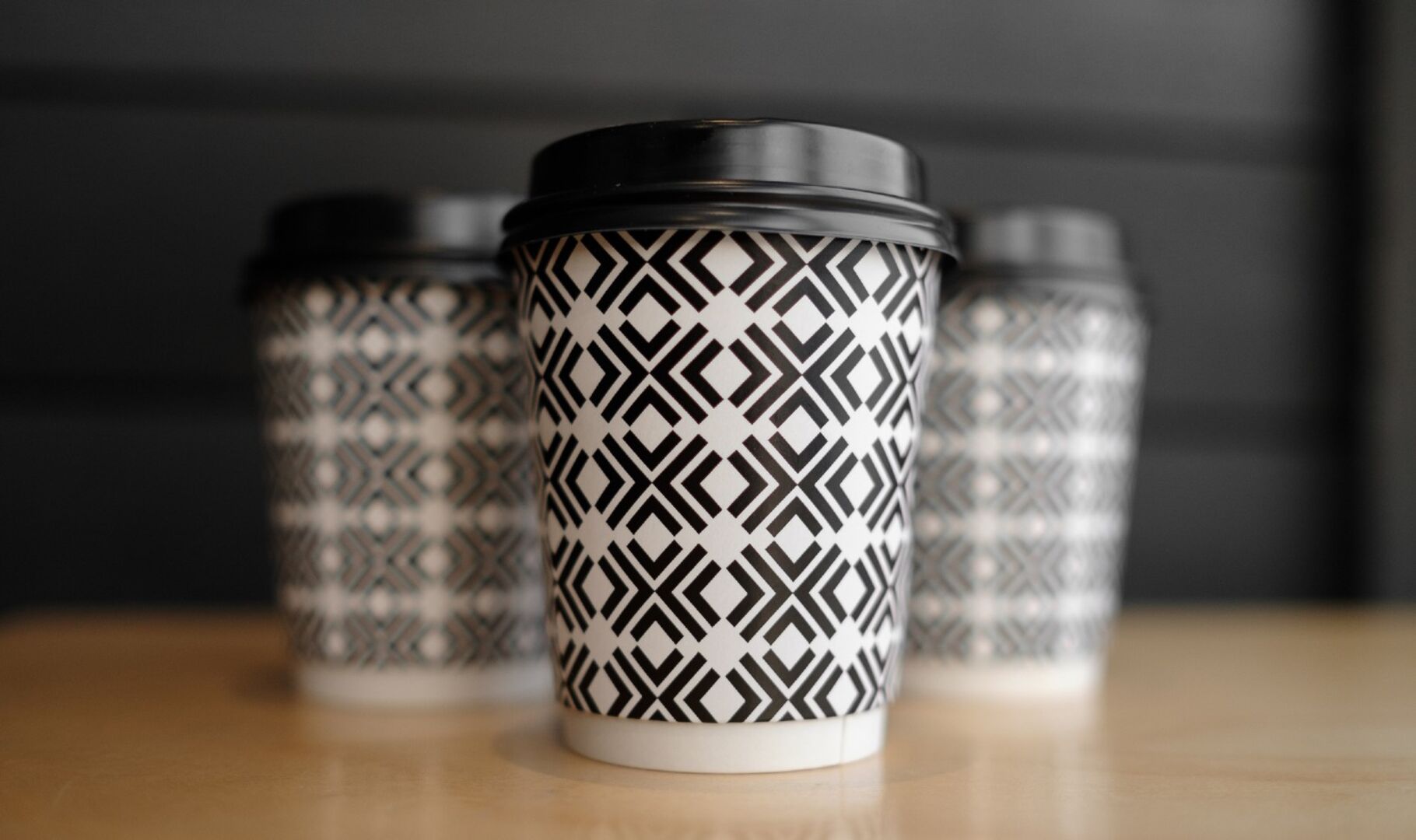 Coffee to go Becher mit schwarzem Muster | Credit: iStock.com/Samoilov