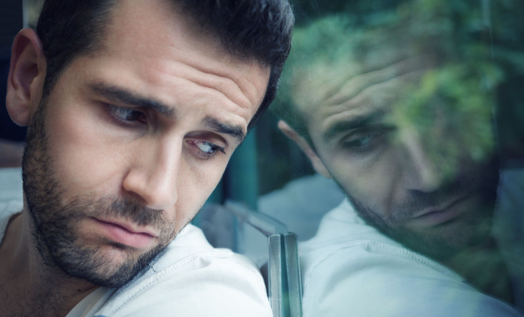 Trauriger Mann schaut aus dem Fenster | Credit: iStock.com/Marjan_Apostolovic