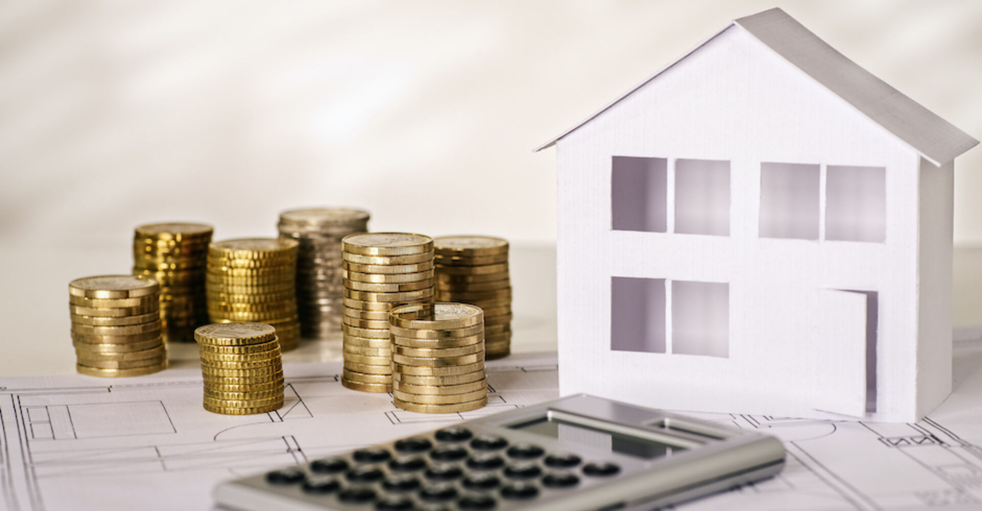 Münzen und Taschenrechner mit Papierhaus | Credit: iStock.com/gopixa