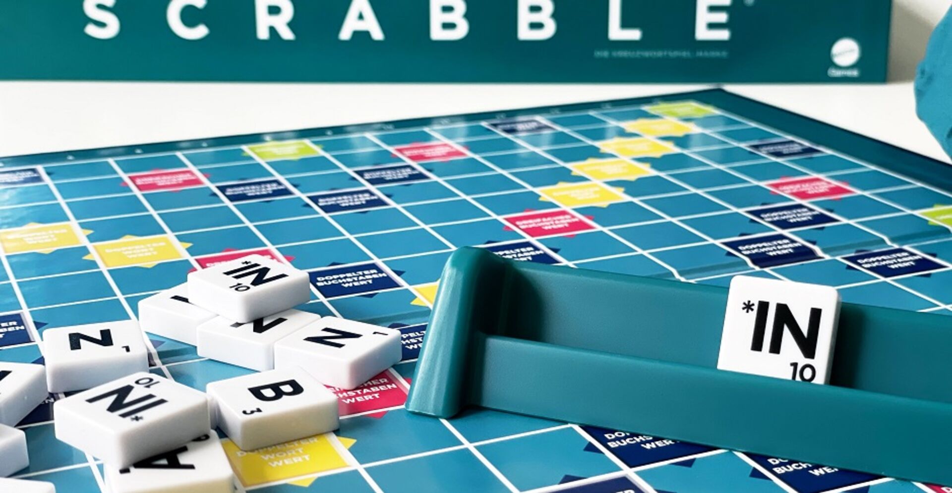 Ein Scrabbel-Spielfeld. Auf dem Buchstabenhalter ein Buchstabendstein. Darauf zu lesen Sternchen-in.