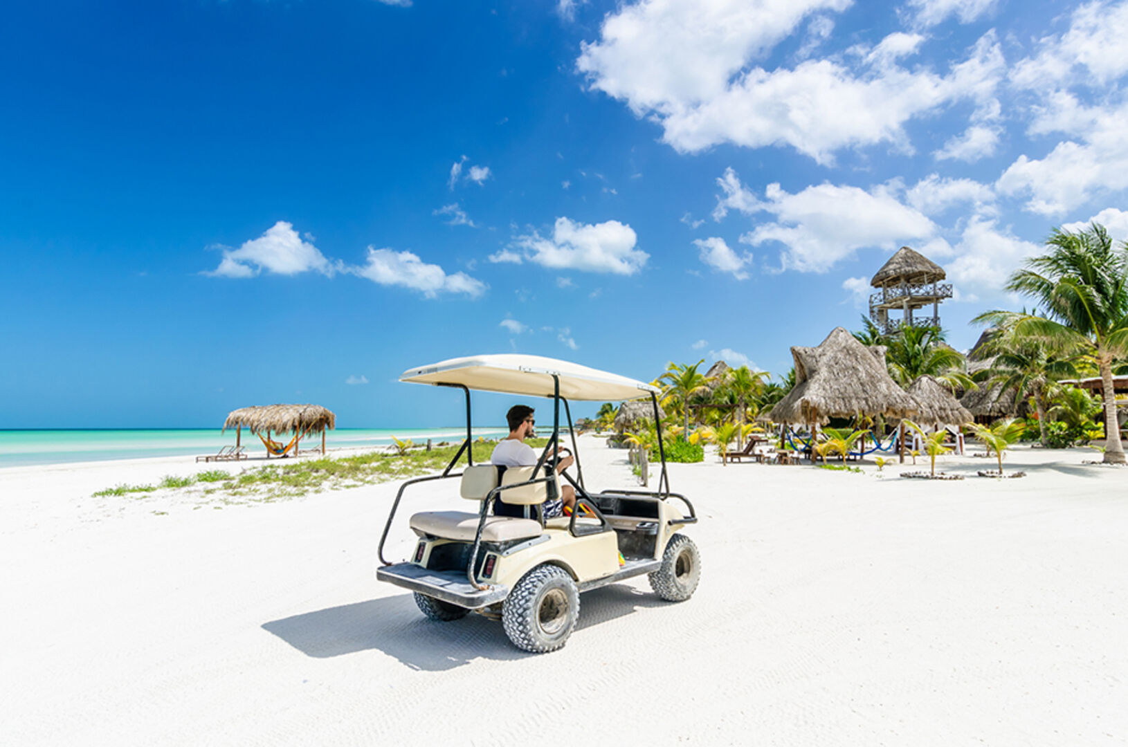 Junger Mann fährt in einem Mini-Mobil den Strand von Holbox ab | Credit: iStock.com/Bodler