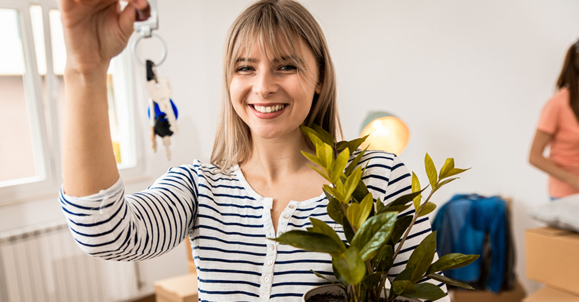 Junge fröhliche Frau wedelt mit ihrem Wohnungsschlüssel in der Hand vor sich hin | Credit: iStock.com/Zoran Zeremski