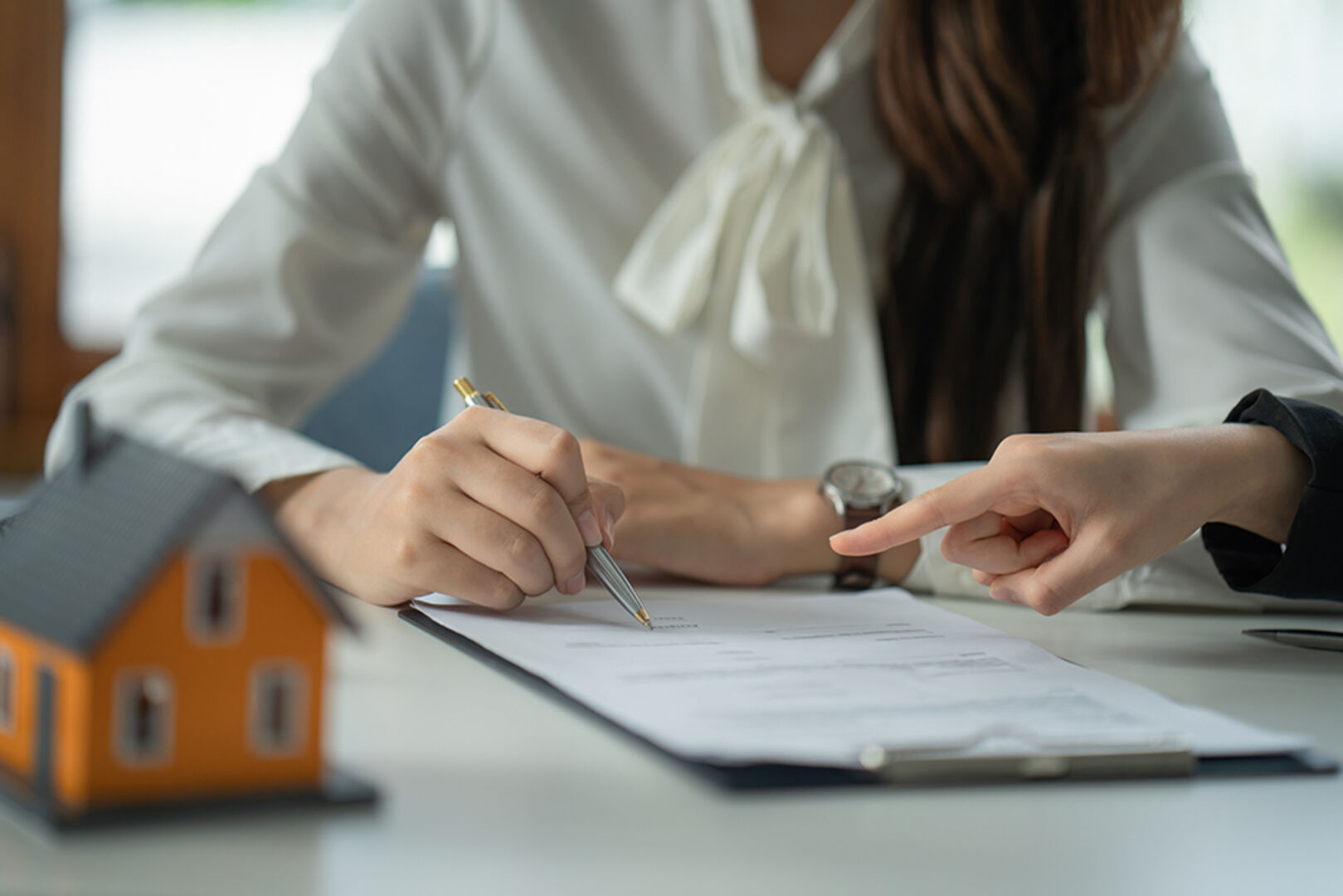 Frau unterschreibt einen Kaufvertrag für eine neue Immobilie | Credit: iStock.com/songsak chalardpongpun