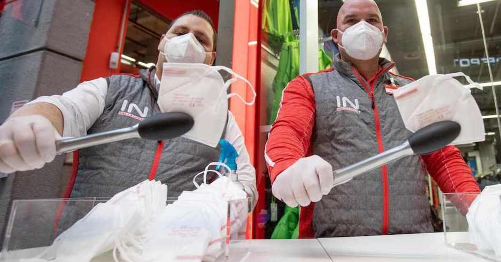 Zwei Angestellte mit Maske verteilen Masken mit Zangen