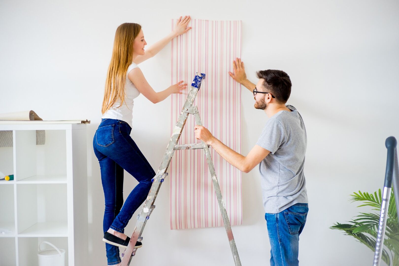 Mann und Frau tapezieren eine Wand | Credit: iStock.com/ElenaNichizhenova