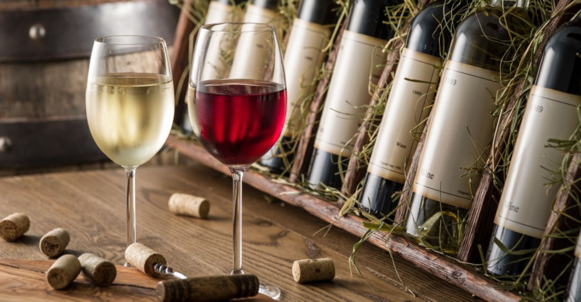 Zwei Weingläser und Weinflaschen stehen auf einem Tisch | Credit: iStock.com/ValentynVolkov