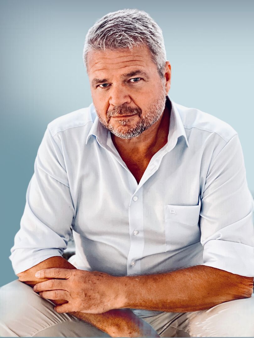 Nahaufnahme von Gerhard Köfer in einem weißen Hemd und einer beigen Leinenhose