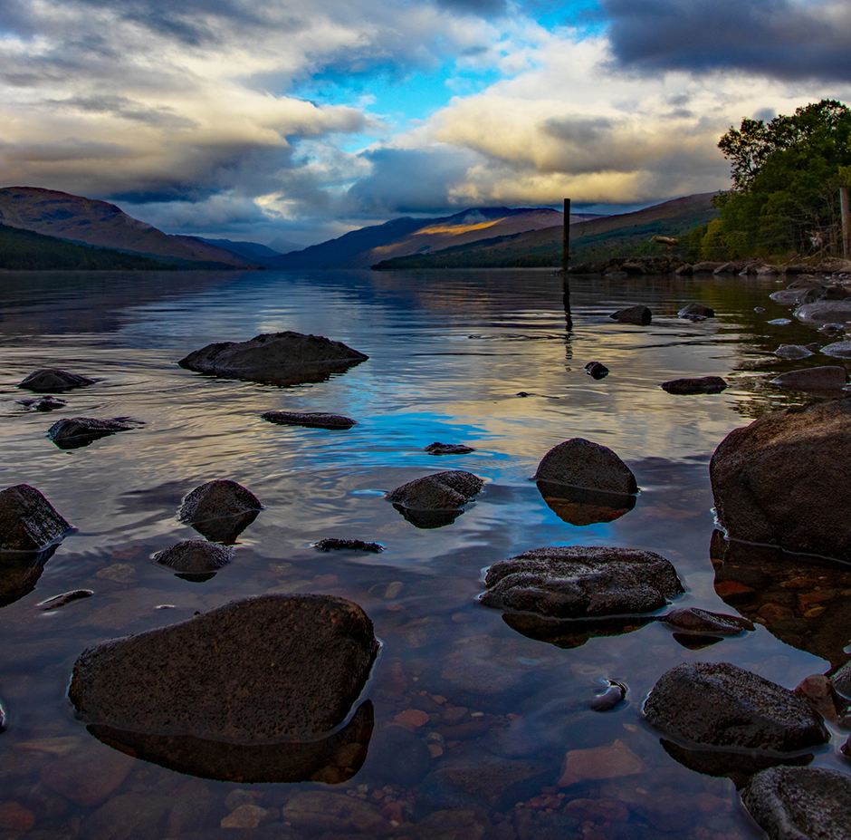 Schottische Seenlandschaften mit großen herausragenden Steinen im Nachmittagslicht | Credit: iStock.com/Marc J F