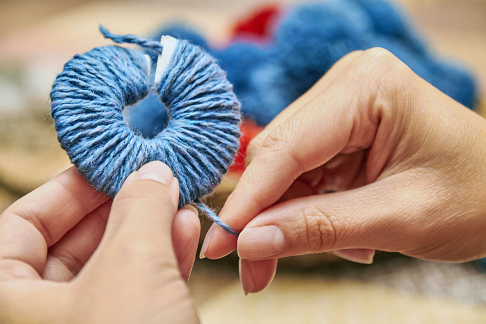 Junge Frau macht Pom Poms aus Wolle | Credit: iStock.com/marketlan