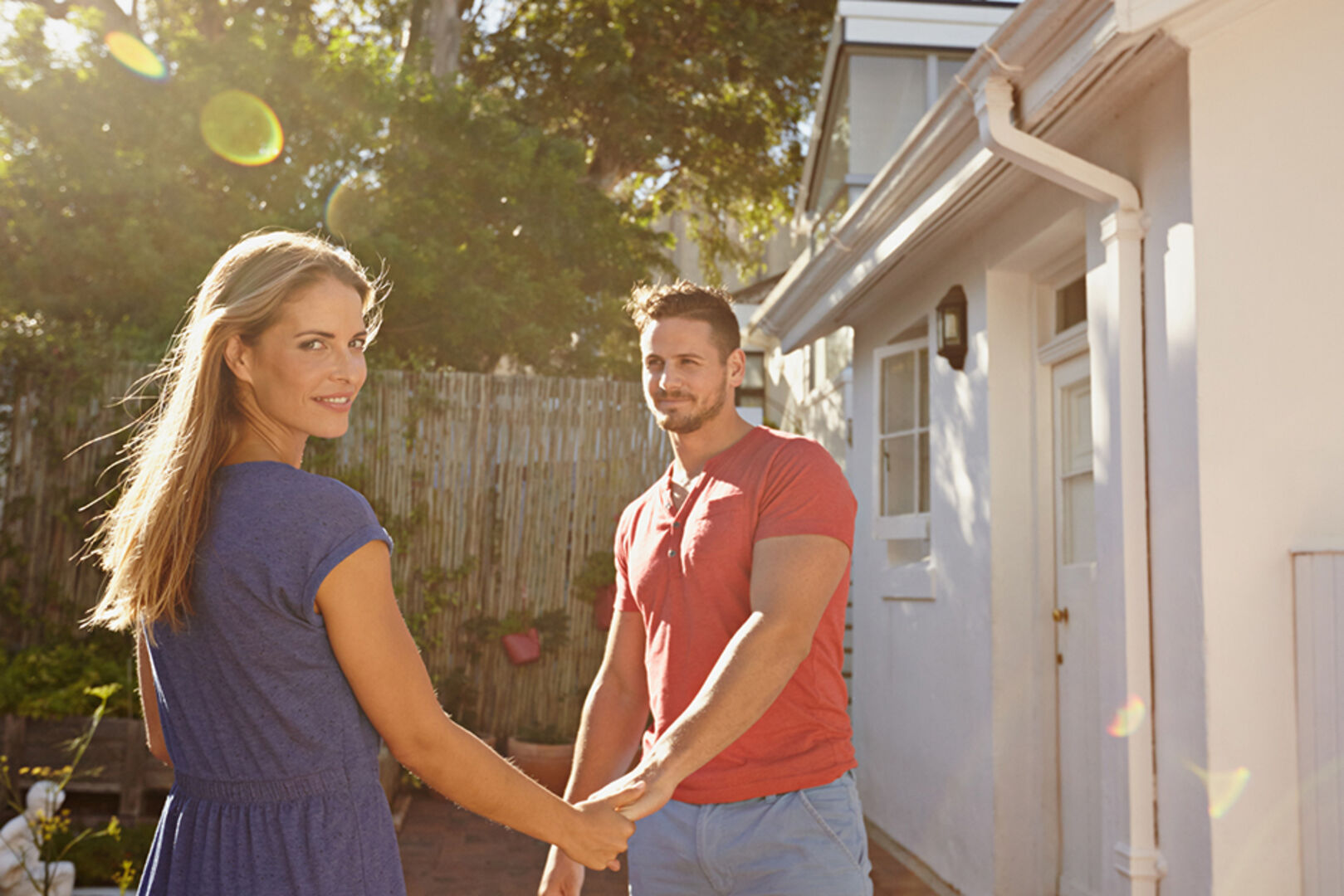 Junges händchenhaltendes Paar vor ihrem Haus an einem sonnigen Tag | Credit: iStock.com/jacoblund